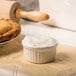 A white dish of lard on a table with a pie and a rolling pin.
