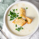 A bowl of Chef Francisco condensed cream of potato soup with croutons and green herbs.