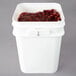 A white pail with a lid filled with frozen red tart pitted cherries.