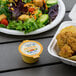A salad and chicken in a Ken's Foods Honey Mustard container.