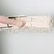 A person holding a Lavex white cotton dry mop with a long handle.