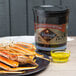 A plate of crab legs and a black container of Wuthrich clarified butter on a table.