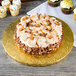 A cake with frosting and pecans on a gold Enjay cake drum.