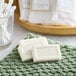 Two Novo Essentials wrapped white face and body soap bars on a green towel.