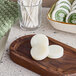 A wooden board with Noble Eco Novo Terra hotel bath soap discs next to bowls of cotton swabs and soaps.