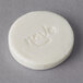 A white round Novo Essentials bath soap bar with text engraved on it.