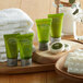 A wooden tray with green Noble Eco hotel shampoo and cream containers, towels, and a green liquid bottle.