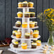 An Enjay white cupcake stand with cupcakes on it.