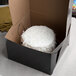 A white cake in an Enjay black bakery box.