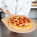 A chef holding a pepperoni pizza on a cutting board.