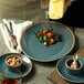A Oneida Terra Verde Dusk porcelain plate with food on a table.