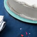 A white cake on a blue Enjay round cake board.