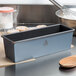 A Matfer Bourgeat steel non-stick bread loaf pan on a counter with a wooden spoon.