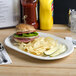 A Tuxton eggshell embossed china platter with a sandwich and chips on it.