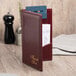 A burgundy leather Menu Solutions guest check presenter with a credit card and a note inside.