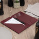 A burgundy leather Menu Solutions check presenter with a credit card pocket on a table.