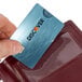 A hand holding a credit card in a blue Menu Solutions guest check presenter.