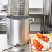 A Vollrath Wear-Ever fryer pot with lobsters and vegetables on a table.