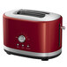A red and silver KitchenAid toaster with 2-slice capacity on a counter.