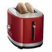 A red KitchenAid toaster with two slices of bread inside.