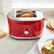 A red KitchenAid toaster with toasted bread in it.