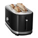 A black KitchenAid long slot toaster with two slices of bread in it.