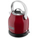 A red KitchenAid electric kettle with silver handles.