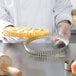 A chef holding a Gobel round fluted tin-plated steel tart pan with a pie in it.