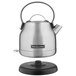 A silver KitchenAid electric kettle on a black stand.