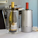 An American Metalcraft clear acrylic wine cooler with a bottle of wine in it on a table.