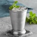 A Barfly stainless steel mint julep cup filled with ice and mint leaves.
