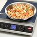A pan of shrimp and vegetables cooking on a Hatco countertop induction range.