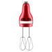 A KitchenAid red hand mixer with stainless steel beaters.