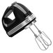 A black and silver KitchenAid hand mixer with attachments.