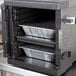 A black metal container with foil trays inside a Cambro ThermoBarrier.