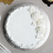 A white cake with frosting on a silver Enjay round cake drum.