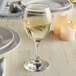 An Anchor Hocking Excellency white wine glass filled with white wine on a table.