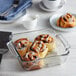 A glass baking dish with cinnamon rolls on a counter.