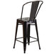 A black metal outdoor counter height stool with a vertical slat back.