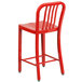 A red metal outdoor counter height stool with a vertical slat back.