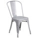 A Flash Furniture silver metal stackable chair with a vertical slat back and drain hole seat.