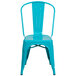 A teal blue metal chair with a slatted back and drain hole.