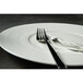A fork and knife on a white Oneida Manhattan porcelain plate.
