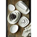 A stack of white rectangular Oneida Stage porcelain platters on a wood surface.