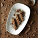 A Oneida Stage warm white porcelain rectangular platter with chocolate bars and chocolate chips.