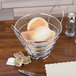 A plastic liner in a metal basket of bread on a table.