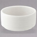 A white round porcelain butter/sauce dish with a textured surface and thin rim.