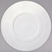 A warm white porcelain coupe plate with a wide rim and a circular pattern.
