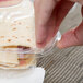 A hand holding a Durable Packaging clear hinged plastic container with food inside.