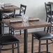 A Lancaster Table & Seating wooden butcher block table with espresso finish on it with chairs and glasses.